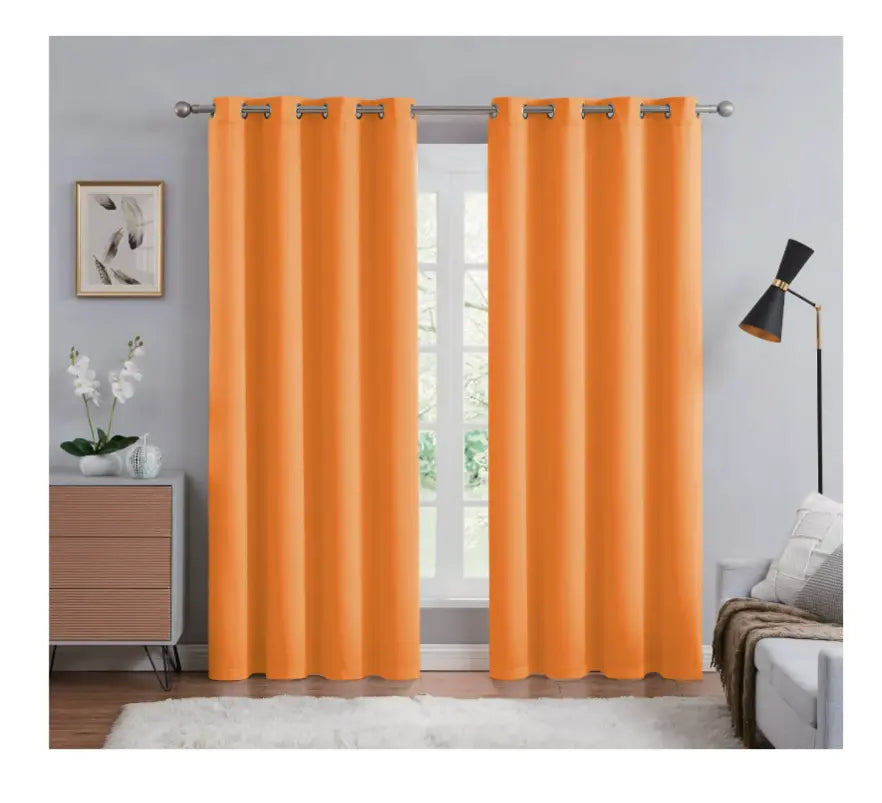 Orange curtains with grommets in a room with a bed and lamp.