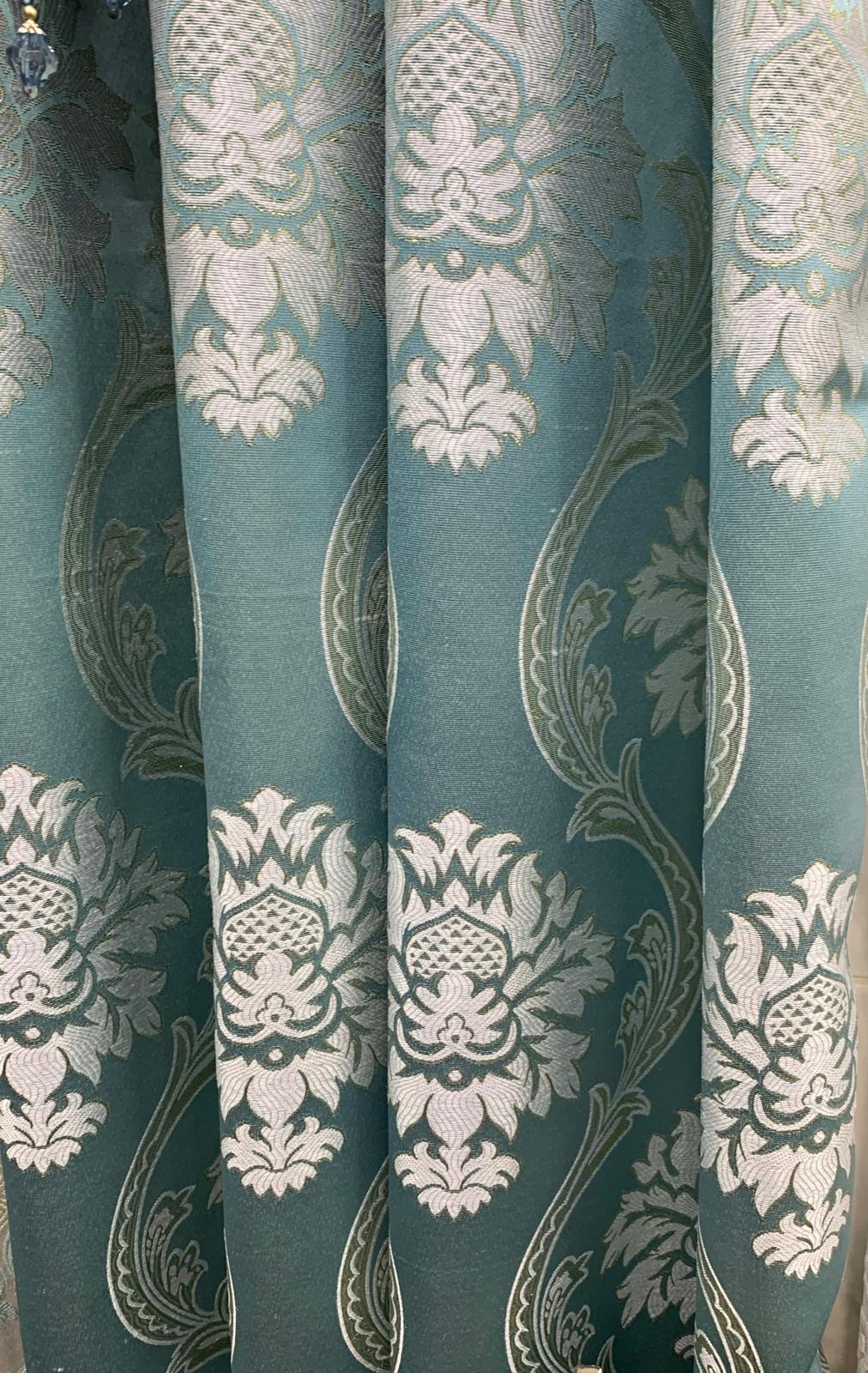 Decorative fabric with intricate white pattern on a teal background