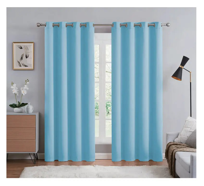 Blue curtains hanging in a room with a lamp, cabinet, and decor items.