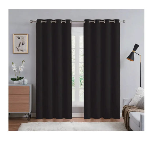 Black curtains hanging in a room with a lamp, plant, and wall art.