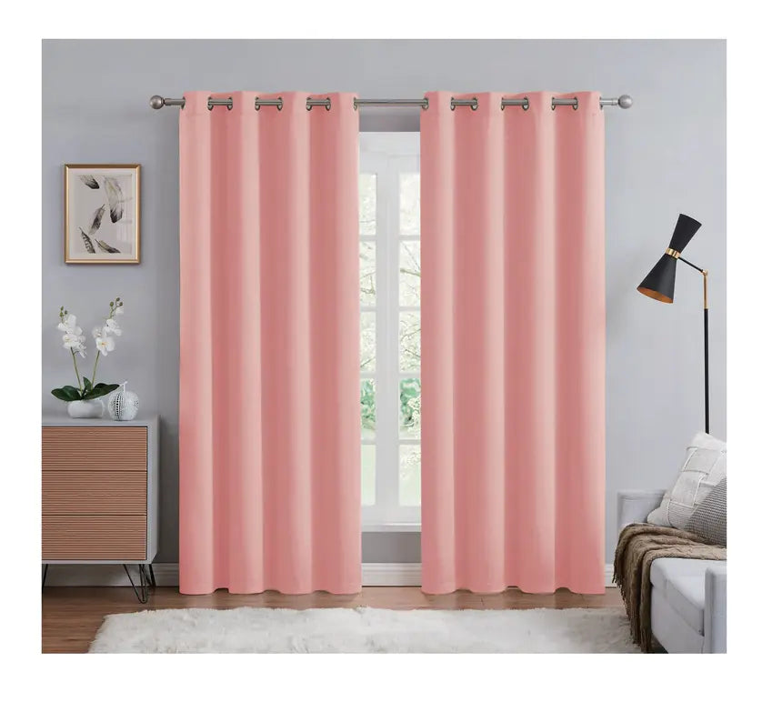 Pink curtains hanging in a room with a window, side table, and lamp.