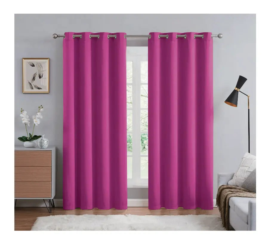Pink curtains hanging in a room with a window, lamp, and decor items.
