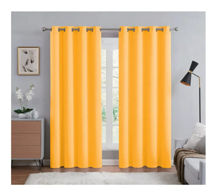 Yellow curtains hanging in a room with a window, side table, and decor items.