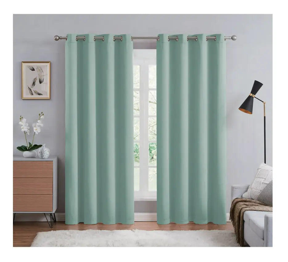 Green curtains hanging in a room with a window, lamp, and decor items.