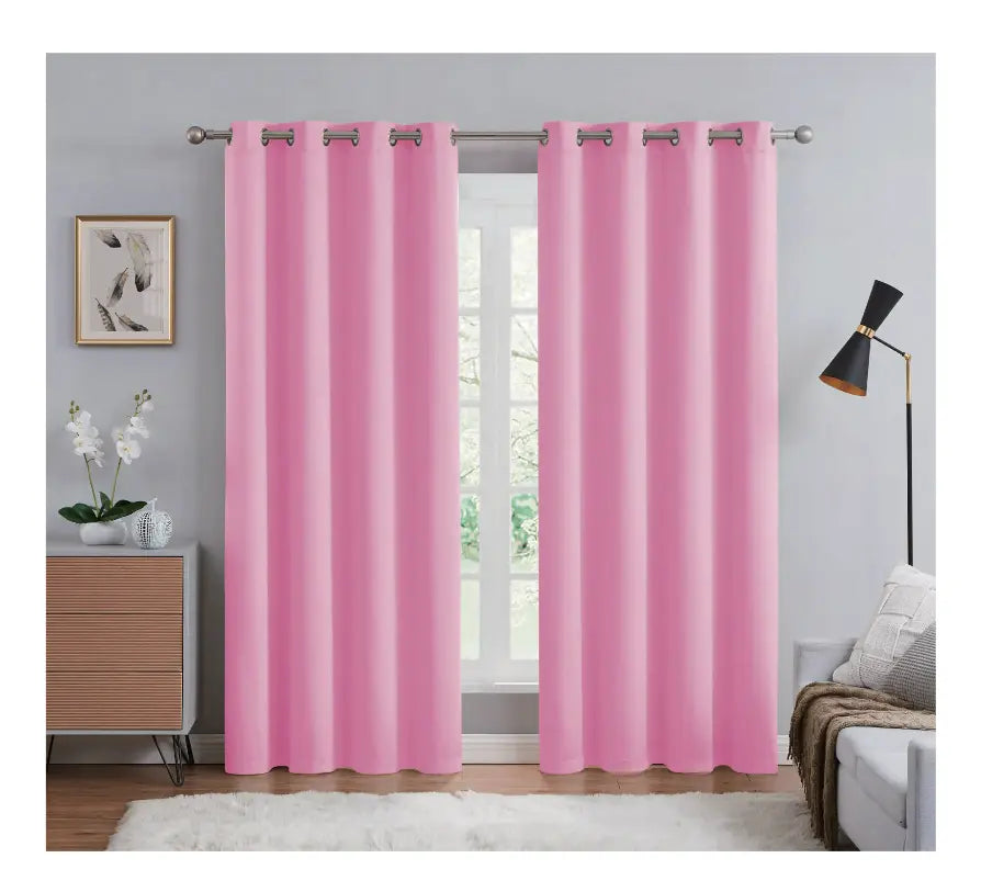 Pink curtains hanging in a room with a window, lamp, and decor items.