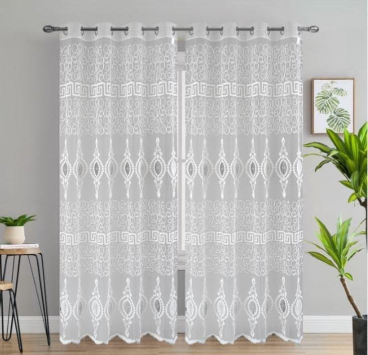 White lace curtain on a gray wall with plants and a stool in the background.