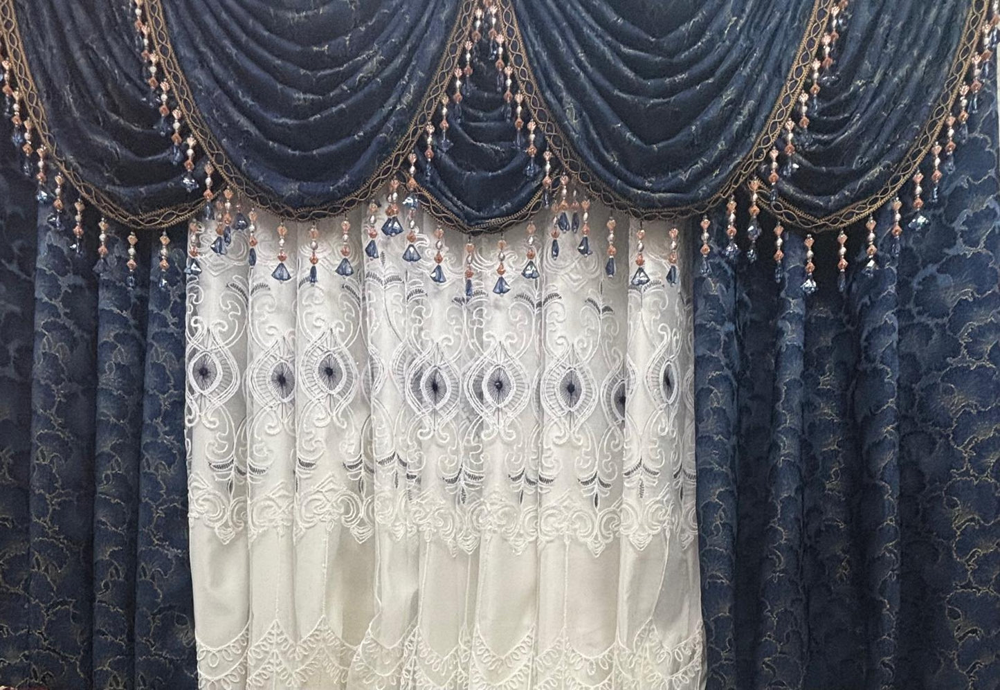Decorative curtain with a blue patterned top section and white lace bottom section.