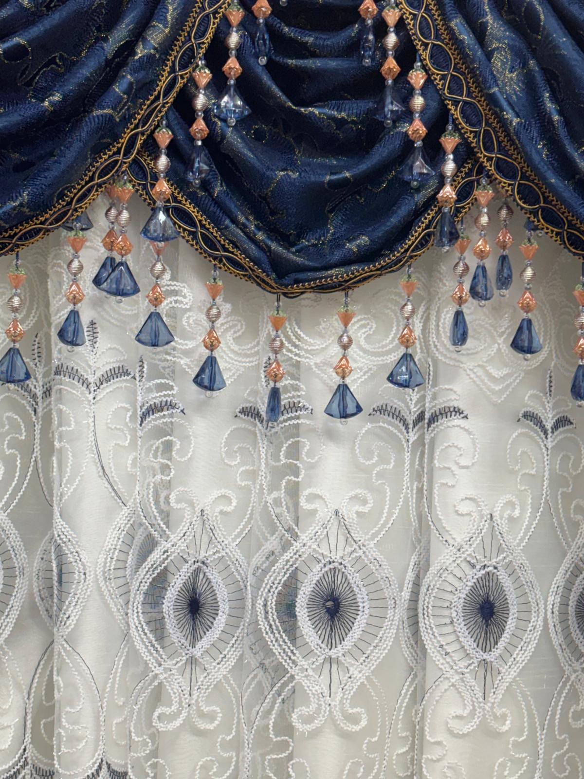 Decorative curtain with blue fabric and bead embellishments on a white lace background