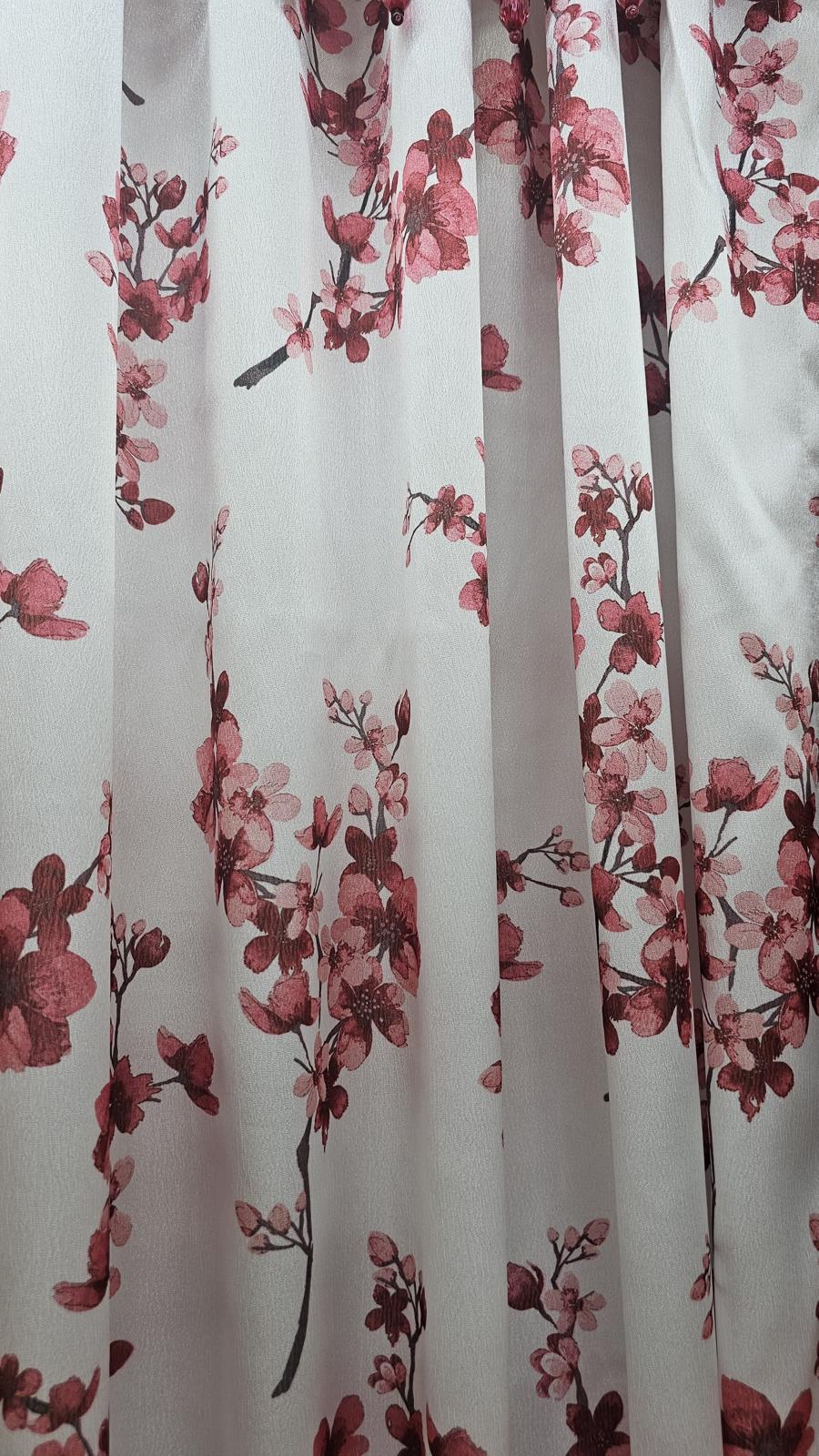 White curtain panels featuring a pink cherry blossom branch pattern, shown hanging with soft folds.