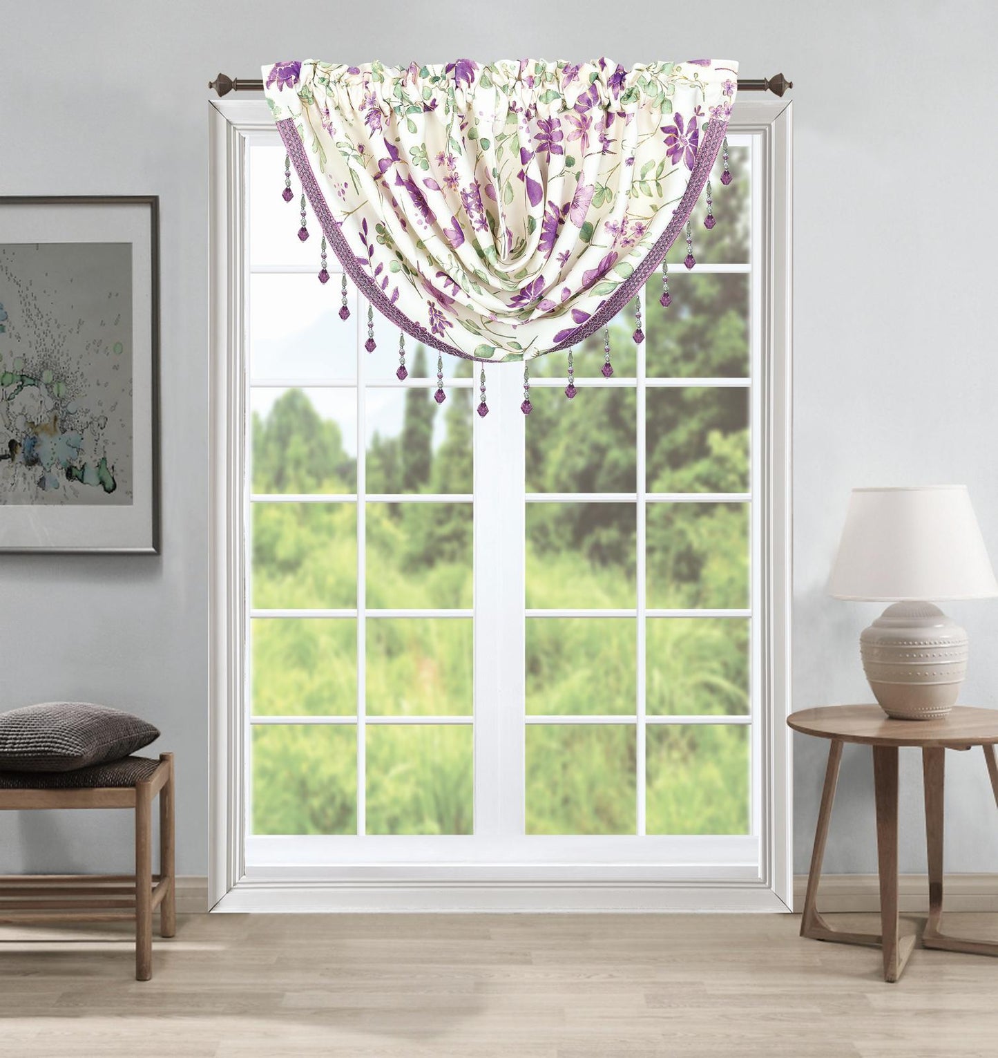 A purple and white floral curtain valance with hanging beads is shown hanging on a window in a styled room with a side table, lamp, and bench.